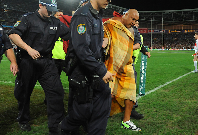 A streaker is escorted off the field during State of 